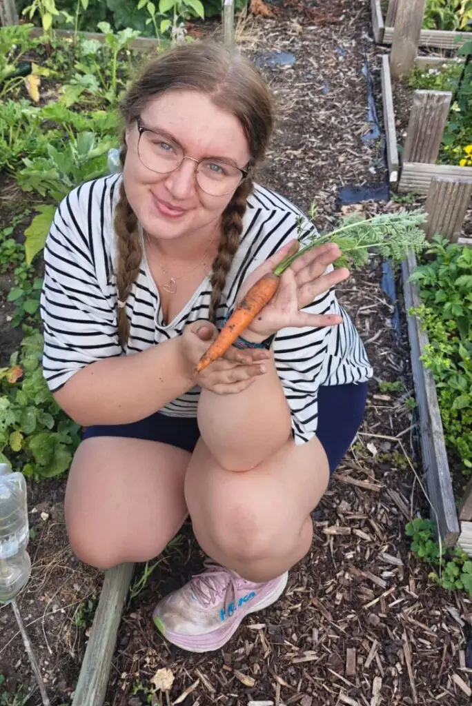 Becky holding a carrot at the allotment
